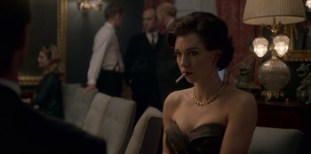Movie still from “The Crown” (2016), created by Peter Morgan – A woman with a cigarette in her mouth; Medium shot, Over the shoulder angle