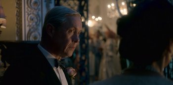 Movie still from “The Crown” (2016), created by Peter Morgan – A man in a tuxedo with a flower in his mouth; Close Up shot, Over the shoulder angle