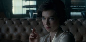 Movie still from “The Crown” (2016), created by Peter Morgan – A woman is holding a cigarette in her hand; Close Up shot, Over the shoulder angle