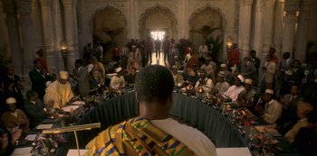 Movie still from “The Crown” (2016), created by Peter Morgan – A group of people sitting around a table; Extreme Wide shot, High angle