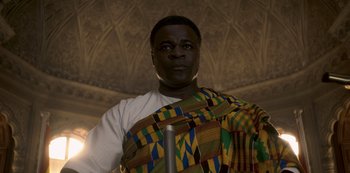 Movie still from “The Crown” (2016), created by Peter Morgan – A man in a colorful shirt is posing for a picture; Close Up shot, Low angle