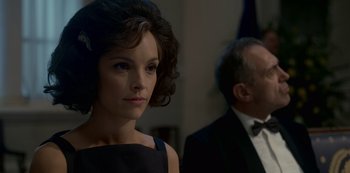 Movie still from “The Crown” (2016), created by Peter Morgan – A woman in a black dress standing next to a man in a tuxedo; Close Up shot, Over the shoulder angle