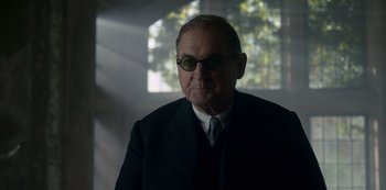 Movie still from “The Crown” (2016), created by Peter Morgan – An older man wearing a suit and tie; Close Up shot, Low angle