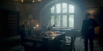 Movie still from “The Crown” (2016), created by Peter Morgan – A room with a desk , chair , and a large window; Wide shot, Low angle