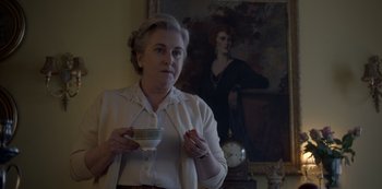 Movie still from “The Crown” (2016), created by Peter Morgan – An older woman is holding a cup of coffee; Medium shot, Low angle