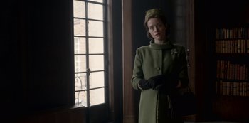 Movie still from “The Crown” (2016), created by Peter Morgan – A woman wearing a green coat and hat; Medium shot, Low angle