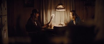 Movie still from “Mud” (2012), directed by Jeff Nichols – A man and a woman sitting at a table with a newspaper; Medium shot, Over the shoulder angle