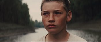 Movie still from “Mud” (2012), directed by Jeff Nichols – A young man with a shaved head and a white shirt; Close Up shot, Over the shoulder angle