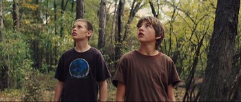 Movie still from “Mud” (2012), directed by Jeff Nichols – Two young boys standing in a wooded area looking up; Medium shot, Low angle