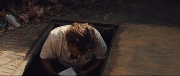 Movie still from “Mud” (2012), directed by Jeff Nichols – A man in white shirt writing on a piece of paper; Medium shot, High angle