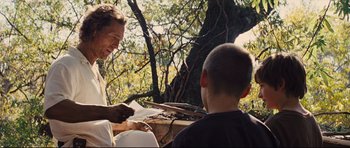 Movie still from “Mud” (2012), directed by Jeff Nichols – A man and a boy sitting next to each other in front of a tree; Medium shot, Over the shoulder angle