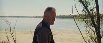 Movie still from “Mud” (2012), directed by Jeff Nichols – An older man standing on the beach near a body of water; Close Up shot, Over the shoulder angle
