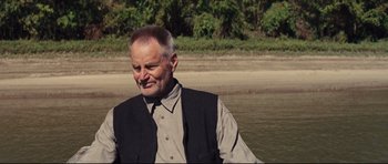 Movie still from “Mud” (2012), directed by Jeff Nichols – An older man wearing a vest standing in the water; Close Up shot, Over the shoulder angle
