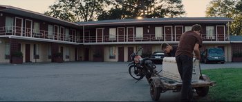 Movie still from “Mud” (2012), directed by Jeff Nichols – A man sitting on the back of a motorcycle parked in front of a motel; Wide shot, Low angle