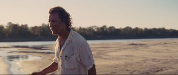 Movie still from “Mud” (2012), directed by Jeff Nichols – A man walking on the beach in a white shirt; Medium shot, Over the shoulder angle