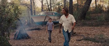Movie still from “Mud” (2012), directed by Jeff Nichols – Two people walking in the woods with a boat in the background; Wide shot, Low angle