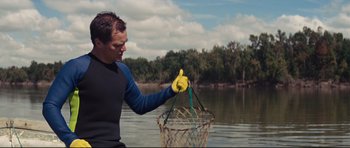 Movie still from “Mud” (2012), directed by Jeff Nichols – A man holding a fishing net while standing in the water; Medium shot, Low angle