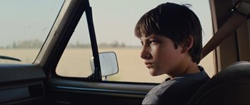 Movie still from “Mud” (2012), directed by Jeff Nichols – A young boy sitting in the driver's seat of a car looking out the window; Close Up shot, Low angle