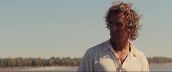 Movie still from “Mud” (2012), directed by Jeff Nichols – A person wearing a white shirt near a body of water; Close Up shot, Over the shoulder angle