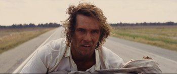 Movie still from “Mud” (2012), directed by Jeff Nichols – A person with long hair on the side of a road; Close Up shot, Over the shoulder angle
