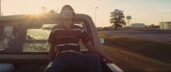Movie still from “Mud” (2012), directed by Jeff Nichols – A man sitting in the back of a pick - up truck; Medium shot, Low angle