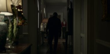Movie still from “The Crown” (2016), created by Peter Morgan – A man walking down the hall way of a house; Wide shot, Over the shoulder angle