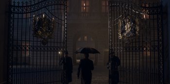 Movie still from “The Crown” (2016), created by Peter Morgan – A man holding an umbrella walking through an open gate; Wide shot, Low angle