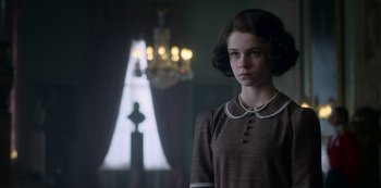 Movie still from “The Crown” (2016), created by Peter Morgan – A young woman standing in front of a window; Close Up shot, Low angle