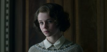 Movie still from “The Crown” (2016), created by Peter Morgan – A young girl with a sweater and a pearl necklace; Close Up shot, Low angle