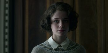 Movie still from “The Crown” (2016), created by Peter Morgan – A young woman wearing a white shirt and a sweater; Close Up shot, Low angle