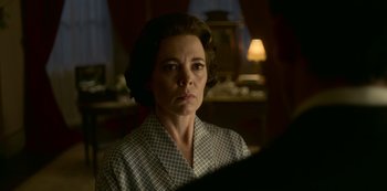 Movie still from “The Crown” (2016), created by Peter Morgan – A woman in a checkered shirt is looking at the camera; Close Up shot, Over the shoulder angle