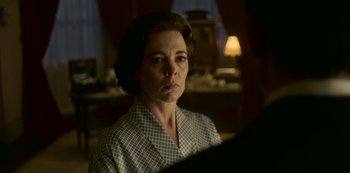 Movie still from “The Crown” (2016), created by Peter Morgan – A woman in a checkered shirt is looking at the camera; Close Up shot, Over the shoulder angle