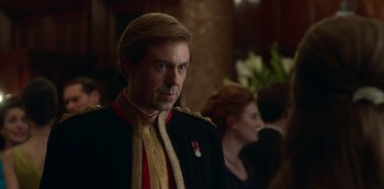 Movie still from “The Crown” (2016), created by Peter Morgan – A man in a military uniform stands in front of a crowd; Close Up shot, Over the shoulder angle