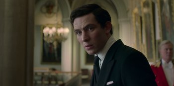 Movie still from “The Crown” (2016), created by Peter Morgan – A man wearing a suit and tie in a room; Close Up shot, Low angle