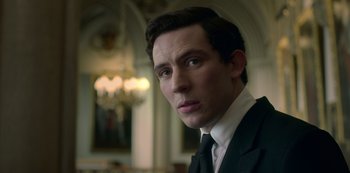 Movie still from “The Crown” (2016), created by Peter Morgan – A person wearing a suit and tie; Close Up shot, Low angle