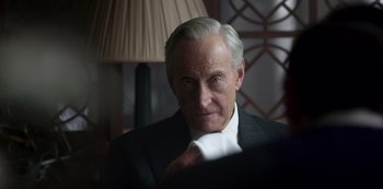 Movie still from “The Crown” (2016), created by Peter Morgan – An older man wearing a suit and tie; Close Up shot, Over the shoulder angle