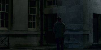 Movie still from “The Crown” (2016), created by Peter Morgan – A man standing in front of a building at night; Wide shot, Low angle