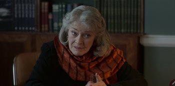 Movie still from “The Crown” (2016), created by Peter Morgan – An older woman wearing a scarf and holding a wine glass; Close Up shot, Over the shoulder angle