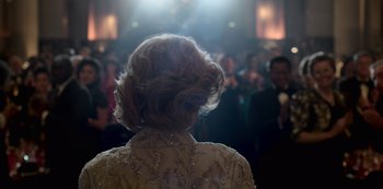 Movie still from “The Crown” (2016), created by Peter Morgan – A woman in a white dress is in front of an audience; Close Up shot, Over the shoulder angle