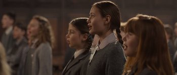 Movie still from “Never Let Me Go” (2010), directed by Mark Romanek – Two young girls standing next to each other in front of a group of people; Close Up shot, Low angle