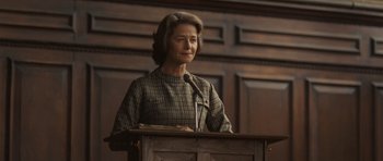 Movie still from “Never Let Me Go” (2010), directed by Mark Romanek – An older woman standing at a lectern in front of a wooden wall; Medium shot, Low angle