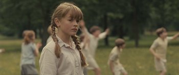 Movie still from “Never Let Me Go” (2010), directed by Mark Romanek – A young girl with pigtails stands in front of a group of children; Medium shot, Over the shoulder angle