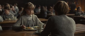Movie still from “Never Let Me Go” (2010), directed by Mark Romanek – A girl sitting at a table with a plate of food; Medium shot, Over the shoulder angle