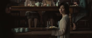 Movie still from “Never Let Me Go” (2010), directed by Mark Romanek – A woman holding a tray of food in a room; Medium shot, Over the shoulder angle