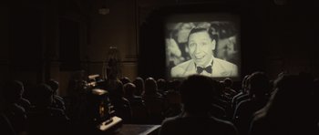 Movie still from “Never Let Me Go” (2010), directed by Mark Romanek – People are watching an old movie on a projector; Medium shot, High angle