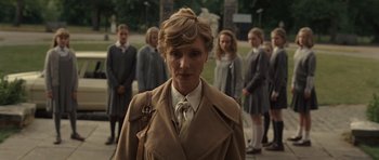 Movie still from “Never Let Me Go” (2010), directed by Mark Romanek – A woman in a trench coat standing in front of a group of girls; Medium shot, Low angle