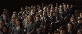 Movie still from “Never Let Me Go” (2010), directed by Mark Romanek – A large group of people sitting in a room together; Wide shot, High angle