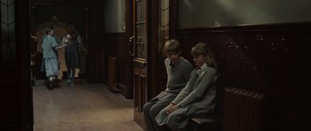 Movie still from “Never Let Me Go” (2010), directed by Mark Romanek – Two young children sitting on a bench in a room; Wide shot, Over the shoulder angle