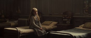 Movie still from “Never Let Me Go” (2010), directed by Mark Romanek – A woman sitting on a bed in front of a window; Medium shot, High angle