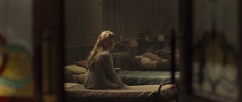 Movie still from “Never Let Me Go” (2010), directed by Mark Romanek – A woman sitting on top of a bed next to a window; Medium shot, Over the shoulder angle
